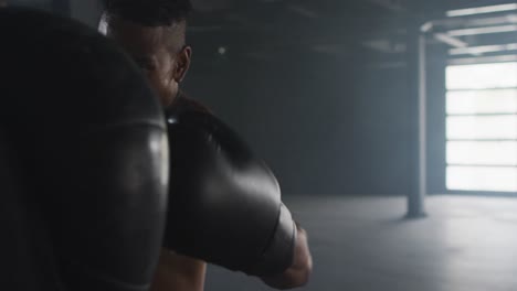 Afroamerikanischer-Mann-Mit-Boxhandschuhen-Trainiert-In-Leerem-Gebäude-Und-Schlägt-Boxsack