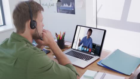 Caucasian-man-using-laptop-and-phone-headset-on-video-call-with-male-colleague