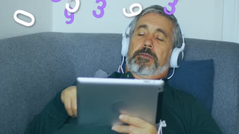 Animation-of-numbers-changing-over-man-with-headphones-on-using-tablet-with-