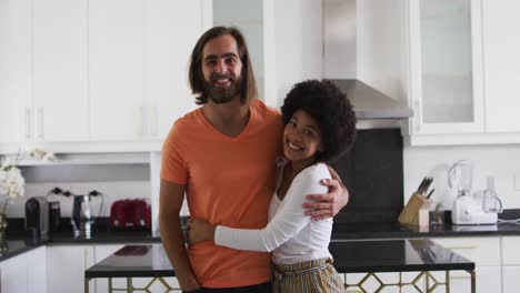 Portrait-of-mixed-race-couple-smiling-and-hugging-in-the-kitchen-at-home