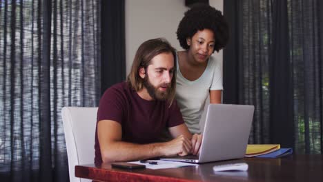 Mixed-race-couple-using-laptop-and-high-fiving-each-other-at-home