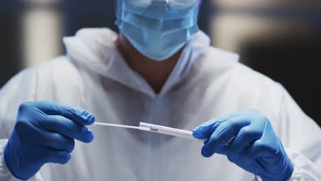 Medical-worker-in-protective-clothing-and-face-mask-examining-patient-swab-test