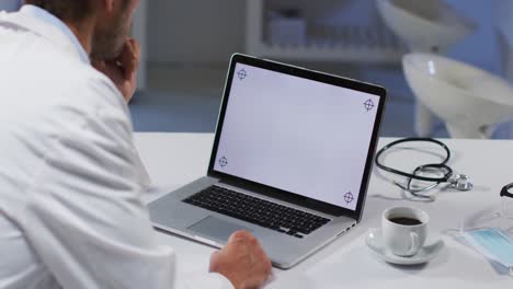 Caucasian-male-doctor-having-video-call-consultation-using-laptop
