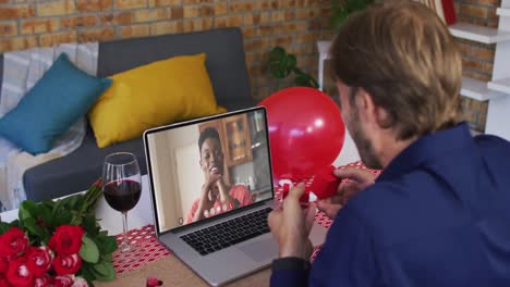 Diverse-couple-on-a-valentines-date-video-call-man-showing-ring-to-smiling-woman-on-laptop-screen