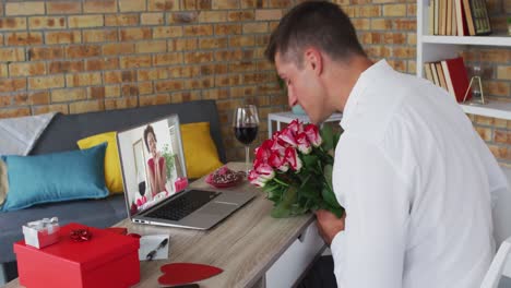 Vielfältiges-Paar-Bei-Einem-Valentinstag-Videoanruf,-Frau-Auf-Laptop-Bildschirm,-Mann-Mit-Blumen