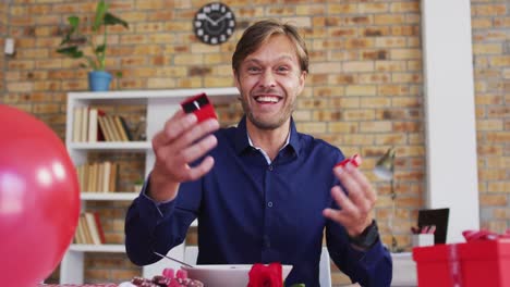 Portrait-of-caucasian-man-showing-a-ring-on-videocall-at-home