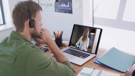 Caucasian-man-using-laptop-and-phone-headset-on-video-call-with-female-colleague