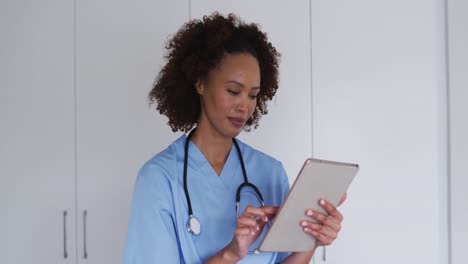 Portrait-of-mixed-race-female-doctor-using-tablet-and-smiling