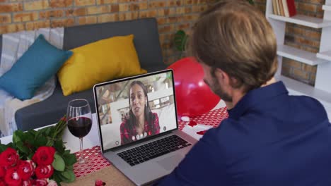 Diverse-couple-on-a-valentines-date-video-call-man-waving-to-woman-on-laptop-screen