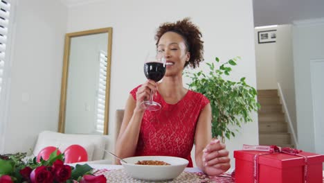 Mixed-race-woman-on-a-valentines-date-video-call,-drinking-wine