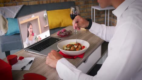 Kaukasisches-Paar-Macht-Videoanruf-Zum-Valentinstag,-Mann-Isst-Essen,-Frau-Auf-Laptop-Bildschirm