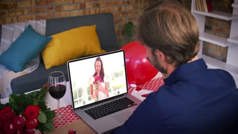 Kaukasisches-Paar-Bei-Einem-Valentinstag-Videoanruf,-Lächelnde-Frau-Auf-Dem-Laptop-Bildschirm,-Die-Blumen-Hält