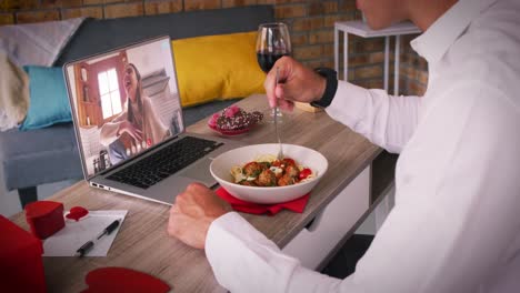 Caucasian-couple-making-valentines-date-video-call-man-eating-meal-woman-laughing-on-laptop-screen
