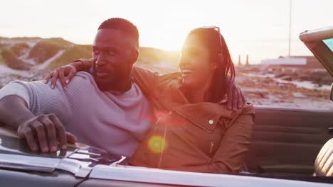 African-american-couple-embracing-each-other-while-sitting-in-the-convertible-car-on-the-road