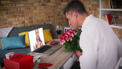Kaukasisches-Paar-Hält-Blumen-Und-Macht-Einen-Videoanruf-Zum-Valentinstag.-Ein-Mann-Wirft-Einer-Frau-Auf-Dem-Laptop-Einen-Kuss-Zu