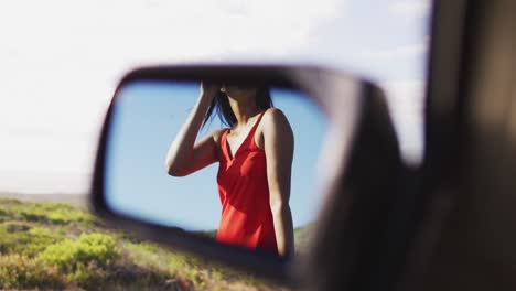 Reflection-of-african-american-woman-standing-on-the-road-from-side-rear-view-mirror-of-the-car