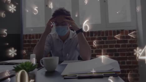 Multiple-numbers-and-symbols-floating-against-stressed-caucasian-man-wearing-face-mask-at-office