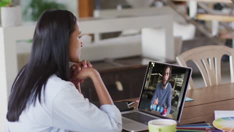 Caucasian-woman-using-laptop-on-video-call-with-male-colleague-working-from-home