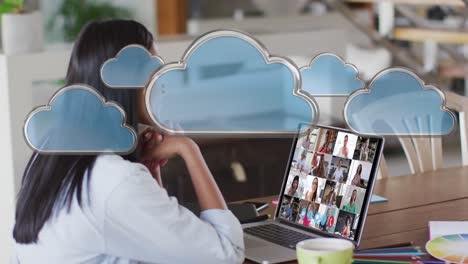 Animation-of-network-of-cloud-icons-over-woman-using-laptop-on-video-call