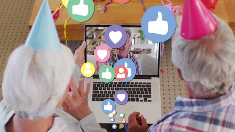 Social-media-icons-floating-against-senior-couple-celebrating-birthday-on-video-call-at-home