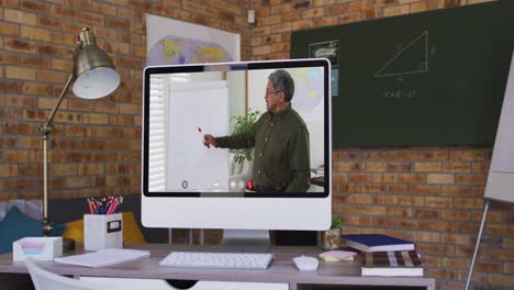 Mixed-race-male-teacher-displayed-on-computer-screen-during-video-call