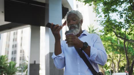 Afroamerikanischer-älterer-Mann,-Der-Im-Firmenpark-Kaffee-Trinkt-Und-Auf-Dem-Smartphone-Spricht