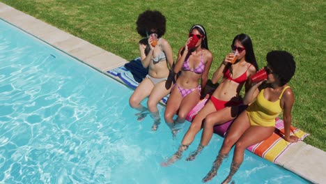 Group-of-diverse-girls-enjoying-their-drinks-while-sitting-by-the-pool