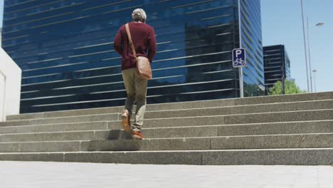 Rear-view-of-african-american-senior-man-walking-up-the-stairs-at-corporate-park