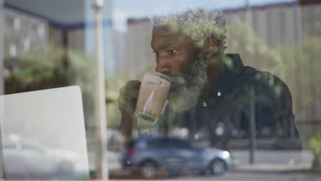 Afroamerikanischer-älterer-Mann-Benutzt-Laptop-Und-Trinkt-Kaffee,-Während-Er-Im-Café-Sitzt