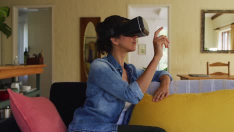Caucasian-woman-wearing-vr-headset,-sitting-on-sofa-at-home