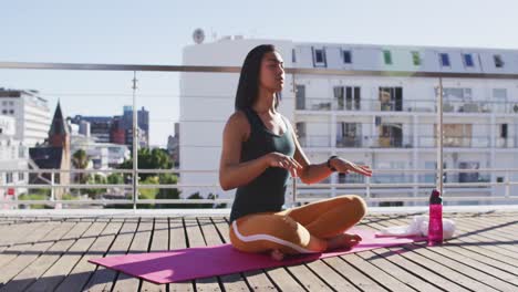 Mixed-race-gender-fluid-person-practicing-yoga-meditation-on-roof-terrace
