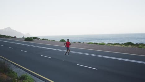 African-american-man-exercising-outdoors-running-on-a-coastal-road