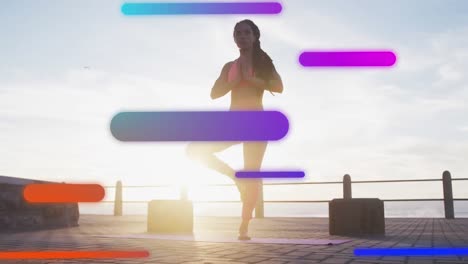 Animation-of-floating-colourful-shapes-over-woman-practising-yoga-on-promenade-by-the-sea