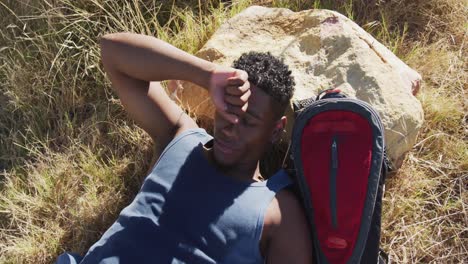 African-american-man-exercising-outdoors-resting-and-lying-in-countryside-on-a-mountain