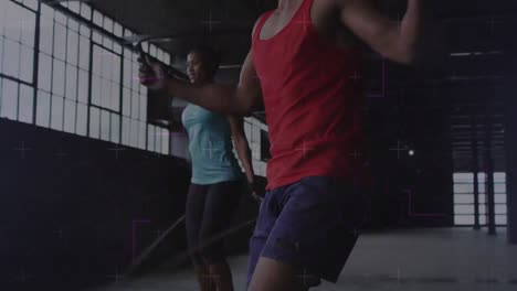Animation-of-light-trails-moving-over-man-and-woman-jumping-with-jumping-ropes,-exercising-in-gym