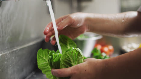 Close-up-of-caucasian-female-chef-washing-vegetables-in-restaurant-kitchen