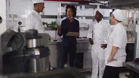 African-american-female-manager-using-tablet-and-talking-with-chefs