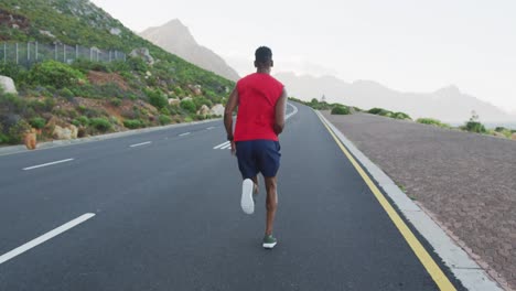 African-american-man-exercising-outdoors-running-on-a-coastal-road