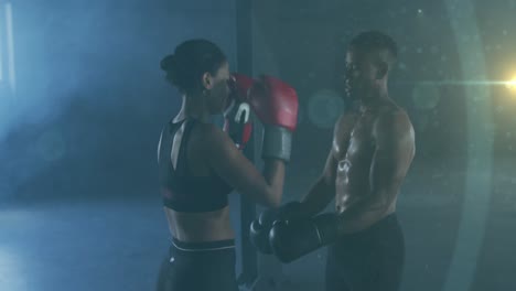 Animation-of-spots-glowing-over-man-and-woman-boxing,-exercising-in-gym