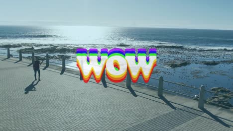 Animation-of-wow-text-over-woman-walking,-exercising-by-seaside