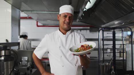 Portrait-of-mixed-race-male-chef-presenting-dish-and-looking-at-camera