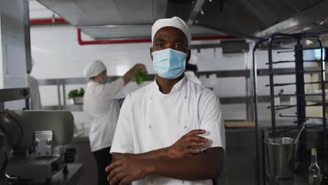 Portrait-of-african-american-male-chef-wearing-face-mask-with-arms-crossed
