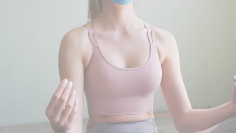 Animation-of-multiple-words-flashing-over-caucasian-woman-wearing-face-mask-meditating