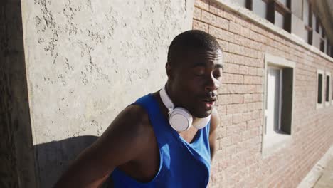 Lächelnder-Afroamerikanischer-Mann-Mit-Kopfhörern,-Der-Draußen-Sport-Treibt