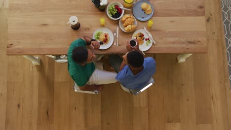 Overhead-view-of-mixed-race-gay-male-couple-having-breakfast-at-table