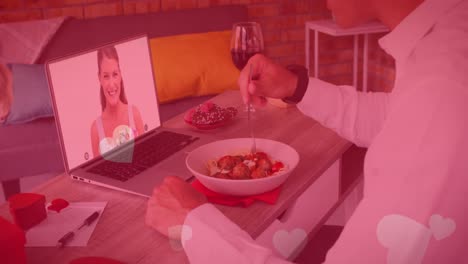 Multiple-heart-icons-floating-over-caucasian-man-having-lunch-while-having-a-video-call-on-laptop