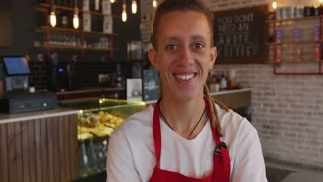 Portrait-of-mixed-race-barista-with-dreadlocks-looking-at-the-camera-and-smiling