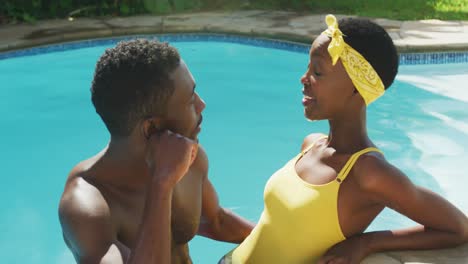 Glückliches-Afroamerikanisches-Paar,-Das-Im-Schwimmbad-Steht-Und-Im-Sonnigen-Garten-Redet-Und-Lächelt