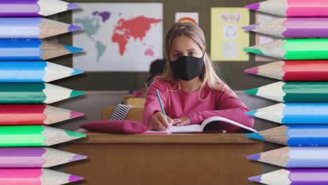 Animation-Von-Bunten-Buntstiften-über-Einem-Mädchen-Mit-Gesichtsmaske,-Das-Im-Klassenzimmer-Sitzt-Und-Schreibt