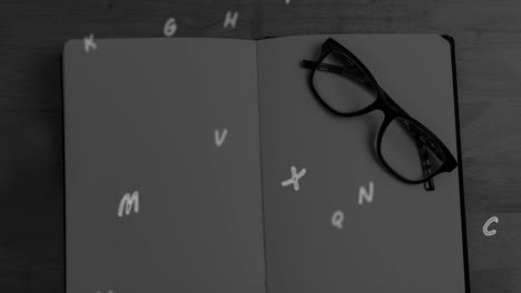 Animation-of-letters-falling-over-notebook-and-glasses